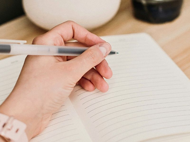cozy scene of someone writing in a journal for self-reflection